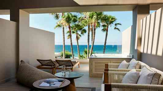 Utendørsområde med sittemøbler, bord og boblebad med havutsikt. (AI-generert tekst)