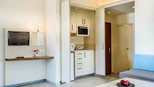 Et hotellrom med et lite kjøkkenområde og stueinnredning. (AI-generert tekst)