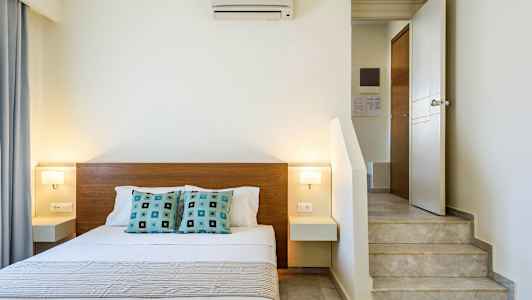 Innendørs bilde av et soverom med en dobbeltseng, moderne innredning og en trapp nær sengen. (AI-generert tekst)