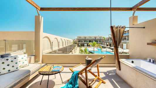 Terrasse med sittemøbler, et badekar og utsikt over et basseng og bygninger. (AI-generert tekst)