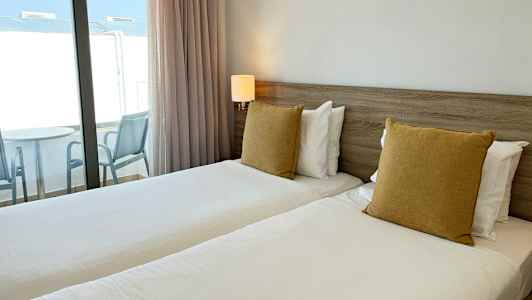 Bilde av et hotellrom med to enkeltsenger og balkong. (AI-generert tekst)