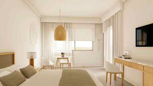 Et lyst hotellrom med en stor seng, en hengende lampeskjerm, et bord med to stoler og en veggmontert TV. (AI-generert tekst)