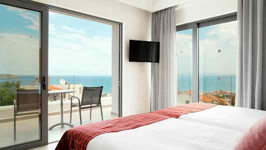 Hotellrom med to senger og dører til en balkong mot havet. (AI-generert tekst)