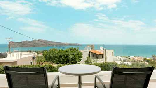 To stoler og et bord på en balkong med utsikt over havet og kystlandskapet. (AI-generert tekst)