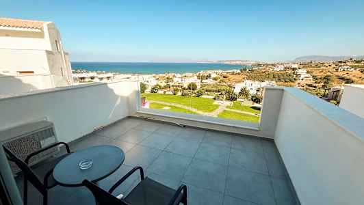 Terrasse med to stoler og bord samt utsikt over havet og boligområde. (AI-generert tekst)