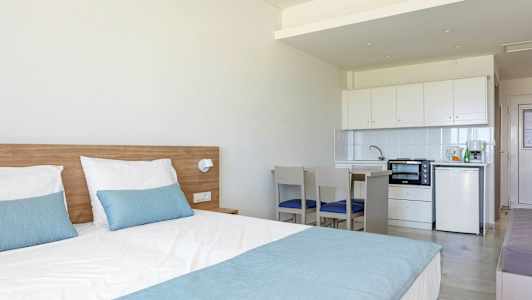 Et hotellrom med en seng og en liten kjøkkenavdeling. (AI-generert tekst)