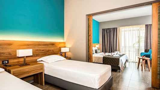 Hotellrom med to enkeltsenger og utsikt mot dobbeltseng gjennom en åpen portal. (AI-generert tekst)