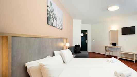 Hotellrom med dobbeltseng, sitteområde, skrivebord og TV. (AI-generert tekst)