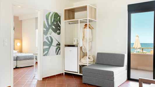 Moderne hotellrom med sittemøbler, åpen garderobe og havutsikt. (AI-generert tekst)