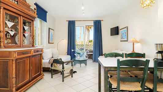 Et lyst oppholdsrom med sofaer, spisebord og stoler samt store vinduer med blå gardiner. (AI-generert tekst)