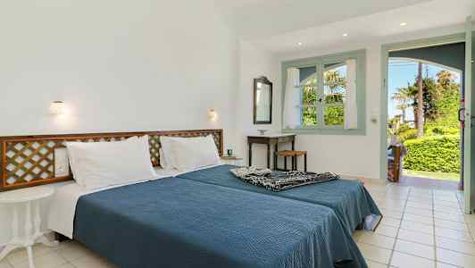 Et soverom med en dobbeltseng, et bord og en åpning mot en frodig hage. (AI-generert tekst)