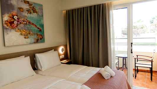 Et hotellrom med to enkeltsenger, et kunstmaleri på veggen og glassdører som fører til en balkong med bord og stoler. (AI-generert tekst)