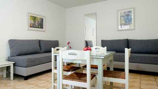 Et rom med to grå sofaer, et hvitt spisebord og fire stoler. (AI-generert tekst)