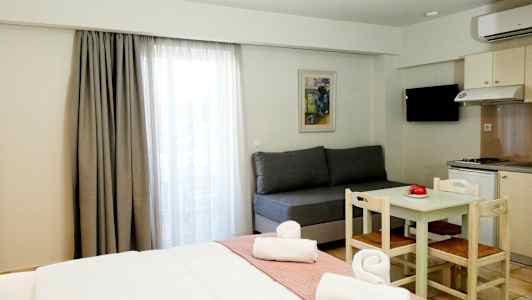 Et hotellrom med en seng, en sofa, et spisebord med stoler og en kjøkkenkrok. (AI-generert tekst)