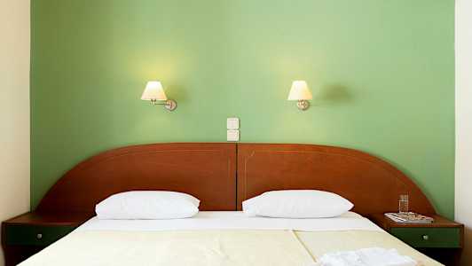 En seng med to sengelamper på en grønn vegg. (AI-generert tekst)