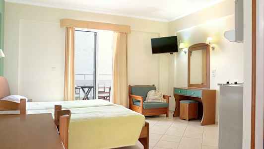 Et hotellrom med to senger, en sitteplass og et skrivebord. Det er også en balkong med møbler. (AI-generert tekst)