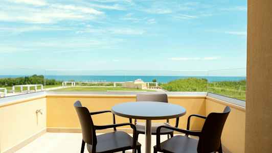 Balkong med bord og stoler med utsikt mot sjøen. (AI-generert tekst)