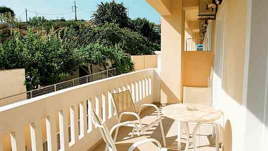 En balkong med hageutsikt, møblert med bord og stoler. (AI-generert tekst)