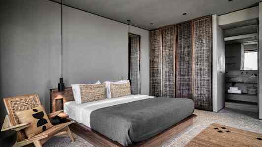 Moderne soveromsinnredning med en stor seng og lenestol. (AI-generert tekst)