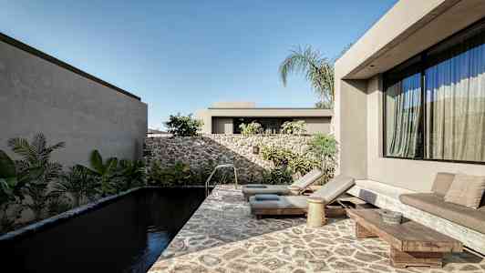 Et moderne uteområde med et basseng av stein, solsenger og planter rundt. (AI-generert tekst)