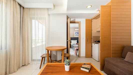 Et hotellrom med enkel innredning, mørke møbler og store vinduer. (AI-generert tekst)