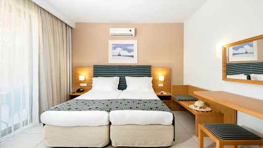 Standardrom med to enkeltsenger, vegglampe og speil. (AI-generert tekst)