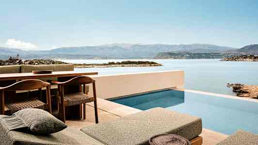 Terrasse med basseng og utsikt over hav og fjell. (AI-generert tekst)