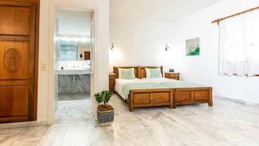 Et soverom med to enkeltsenger og en dør som leder til et bad. (AI-generert tekst)