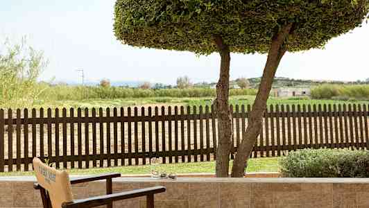 Utsikt fra en terrasse mot et trestak og et grønt landskap. (AI-generert tekst)