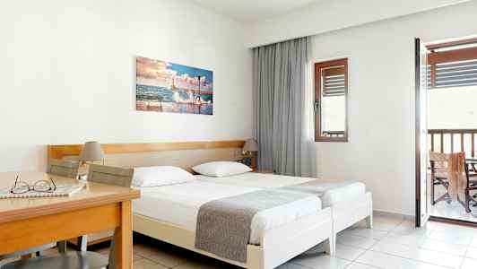 Hotellrom med to enkeltsenger, et trebord og stol samt balkong. (AI-generert tekst)