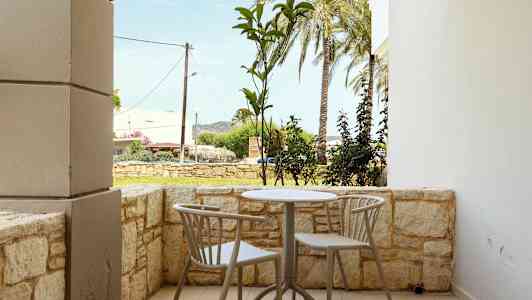 En uteplass med et bord og to stoler, omgitt av en lav steinmur. (AI-generert tekst)