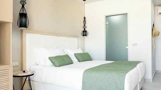 Et rom med en dobbeltseng med grønne sengeklær og puter. (AI-generert tekst)