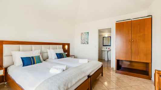 Et hotellrom med to oppredd seng, et skap og inngang til et bad. (AI-generert tekst)