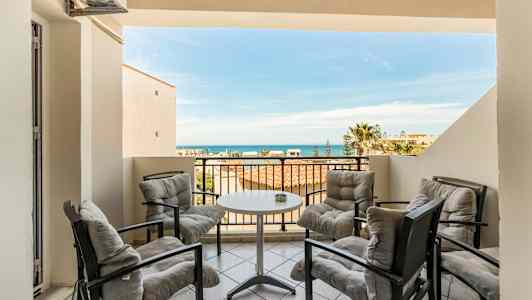 Terrasse med fire sitteplasser rundt et bord, havutsikt i bakgrunnen. (AI-generert tekst)