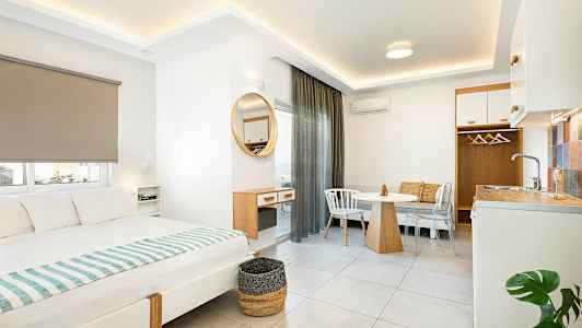 Interiør av et moderne hotellrom med seng, spisebord og liten kjøkkenkrok. (AI-generert tekst)