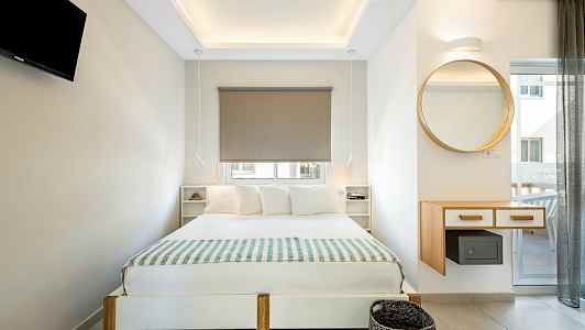 Moderne innredet soverom med dobbeltseng, vegghengt TV og et rundt speil. (AI-generert tekst)