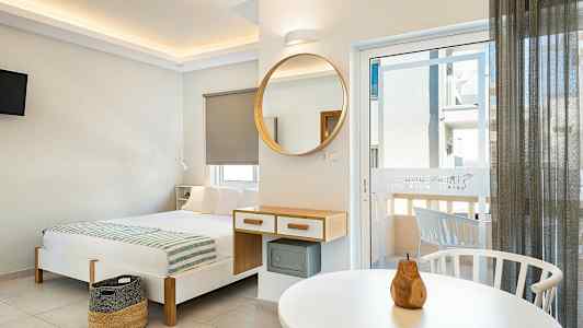 Moderne innredet hotellrom med seng, speil og balkongdør. (AI-generert tekst)