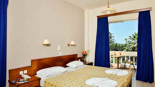 Interiør av et soverom med en dobbeltseng, nattbord og utsikt mot en balkong. (AI-generert tekst)