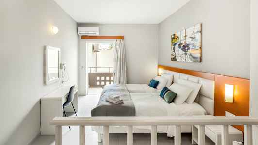 Rom med to senger, et skrivebord og en balkong. (AI-generert tekst)