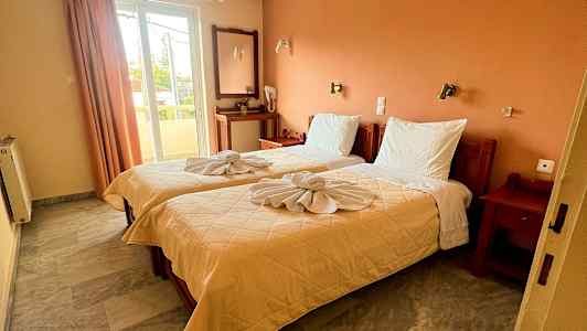 Et hotellrom med to enkeltsenger, dekorert med brettede håndklær. (AI-generert tekst)