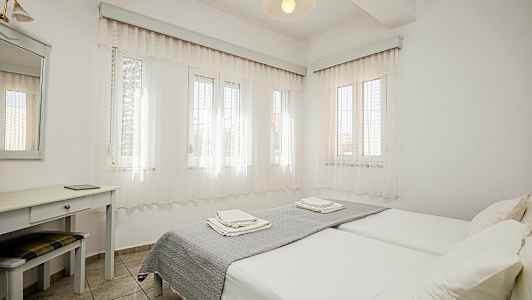 Lyst soverom med to enkeltsenger, skrivebord og speil. (AI-generert tekst)