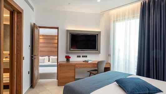 Et hotellrom med moderne innredning, en seng, et skrivebord og en TV. (AI-generert tekst)