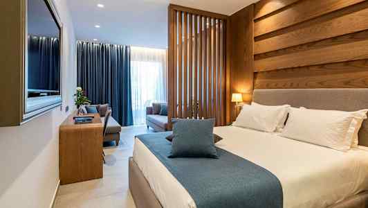 Et hotellrom med en stor seng, sitteområde og trepanel. (AI-generert tekst)