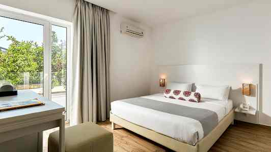 Et soverom med en dobbeltseng, nattbord og skrivebord nær vinduet. (AI-generert tekst)