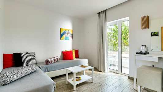 Et rom med sitteplass og bord, innredet med lyse farger. (AI-generert tekst)