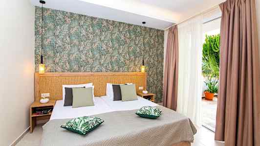 Soverom med dobbeltseng, grønne puter og dekorert vegg. (AI-generert tekst)