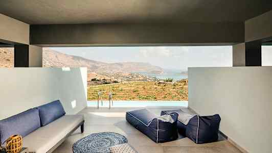 En lounge med sitteplasser og utsikt over et landskap og hav. (AI-generert tekst)