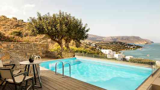 Et basseng med utsikt over havet og en skråning med hus. (AI-generert tekst)