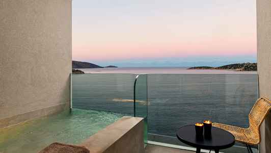 Utsikt over havet fra en balkong med et privat basseng, bord og stol. (AI-generert tekst)