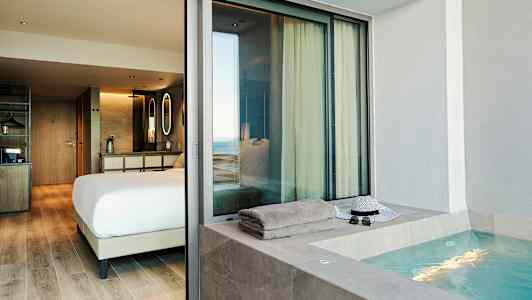 En hotellsuite med et soverom og et utendørs boblebad. (AI-generert tekst)